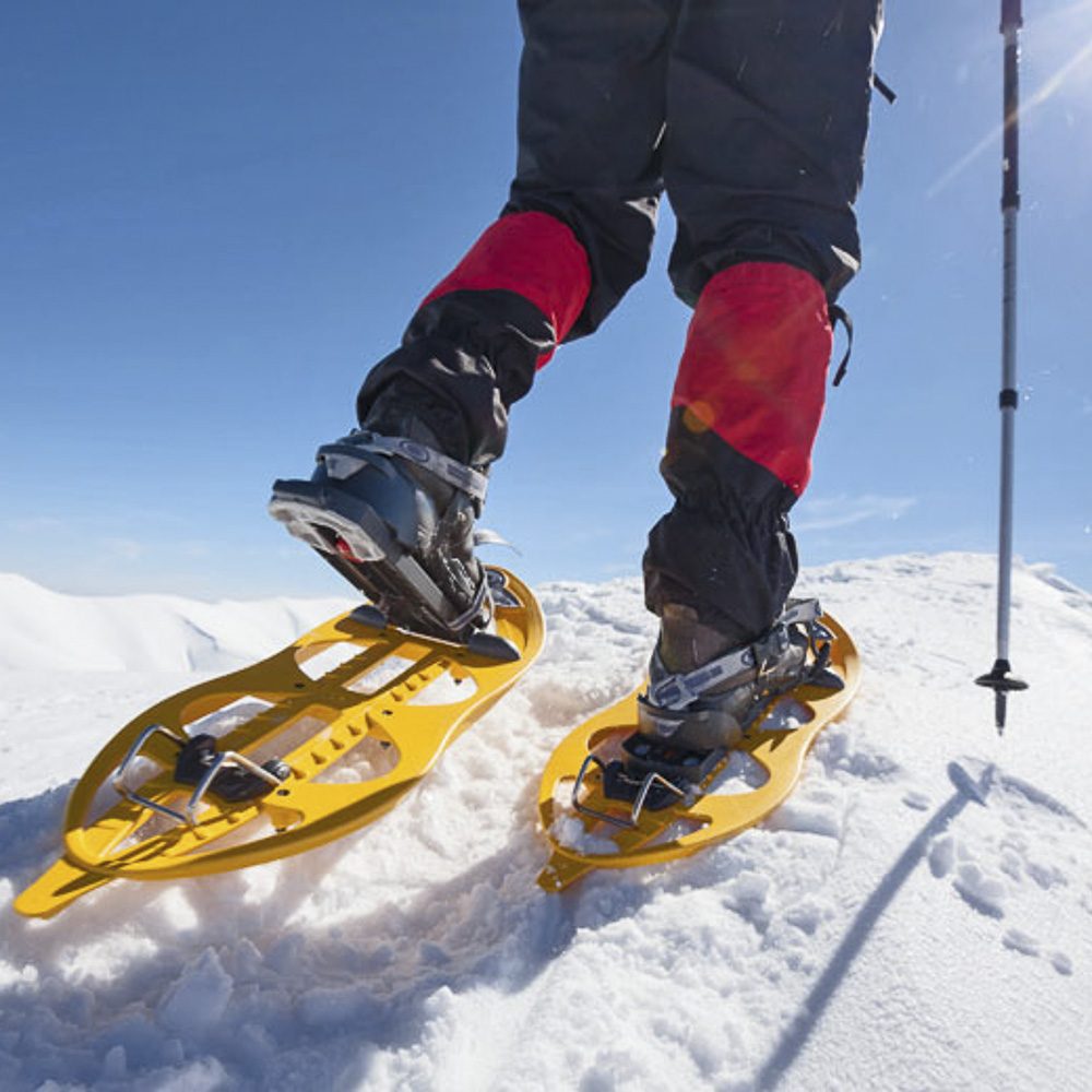 Hiker snowshoeing in winter mountains during sunny day